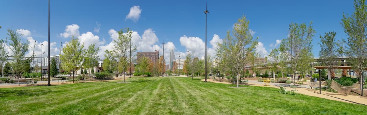 A grassy field with trees and buildings in the background — Omaha, NE